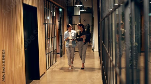 Smiling businesswoman
talking while walking down
an office hallway