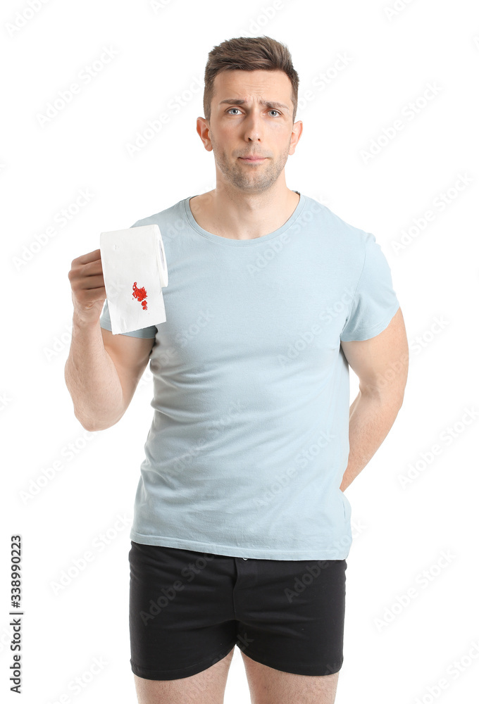 Young man holding toilet paper with blood spot on white background. Hemorrhoids concept Young man holding toilet paper with blood spot on white background. Hemorrhoids concept