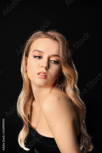 Young blonde with beautiful hair on dark background