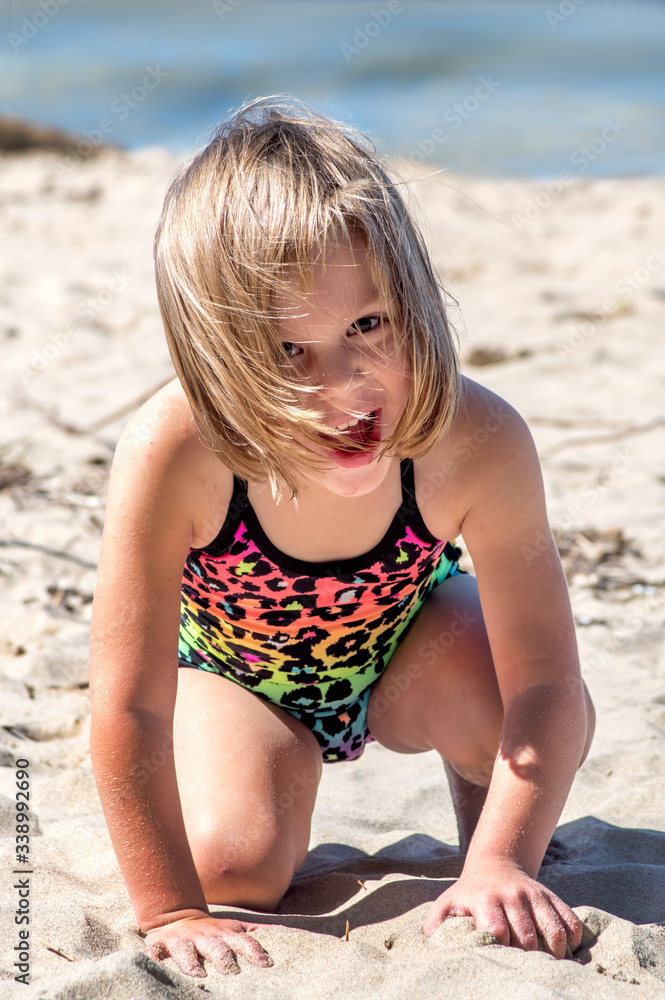 Laughing little girl plays in the sand on the warm summer beach Laughing little girl plays in the sand on the warm summer beach