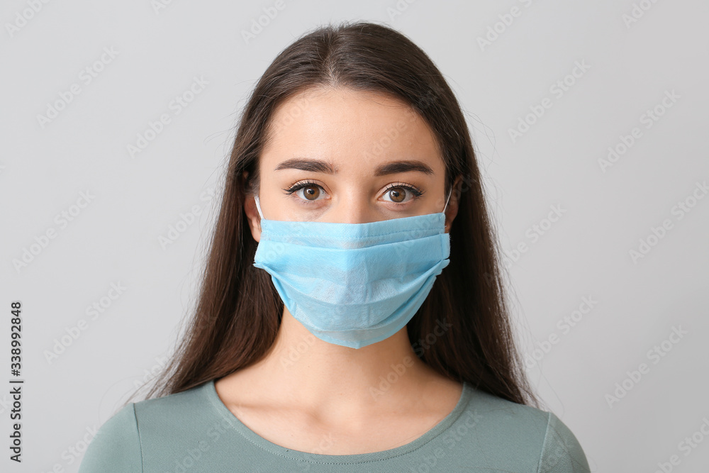 Young woman wearing medical mask against grey background Young woman wearing medical mask against grey background
