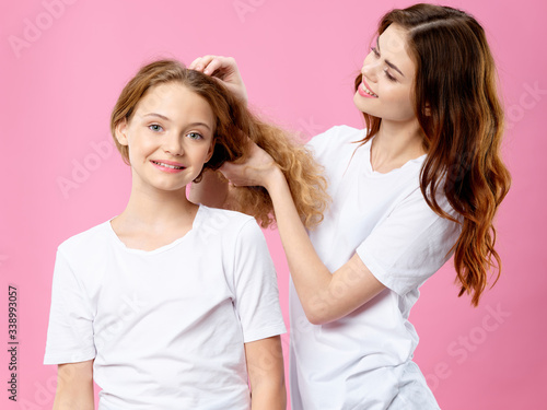 Mom and daughter in white t-shirts care is a communication joy pink background