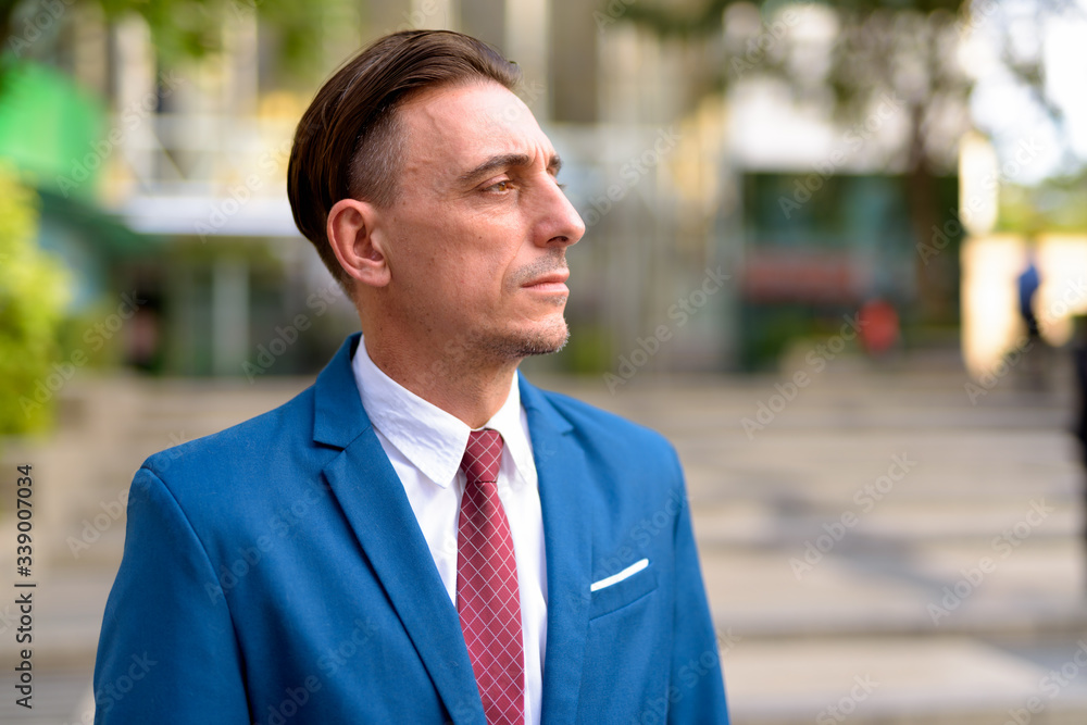 Mature handsome Italian businessman relaxing outside of the building Mature handsome Italian businessman relaxing outside of the building