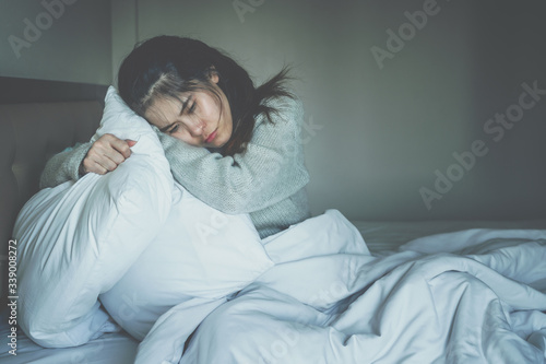 Portrait of depressed woman sitting alone on the bed in the bedroom. Conceptual of bad condition of broken hearted, sadness, loneliness or depress woman.