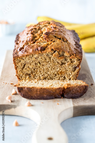 A straight on vertical view of a banana bread loaf that is sliced into with one slice in front.