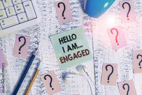 Conceptual hand writing showing Hello I Am... Engaged. Concept meaning He gave the ring We are going to get married Wedding Writing tools and scribbled paper on top of the wooden table photo