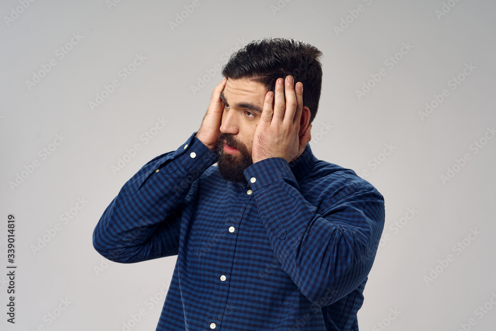 Side view of a man in a blue shirt touching his head with his hands Side view of a man in a blue shirt touching his head with his hands