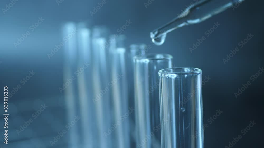 Close up of pipette with liquid inside and water drop in test tubes