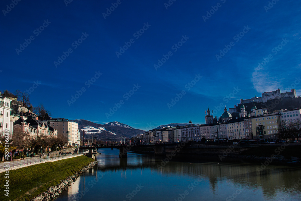 A river in the middle of two side buildings with the bridge and the reflection of blue sky, Austria