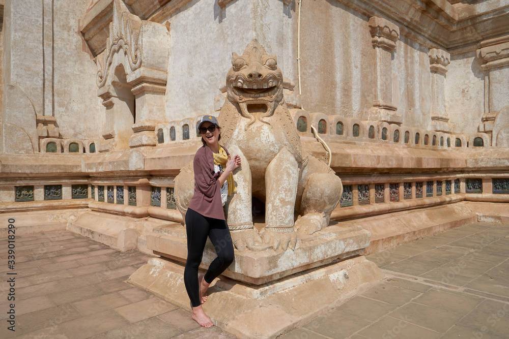 Woman tourist and a sculpture of a guardian lion in the Ananda Temple, old Bagan, Myanmar, Burma.   