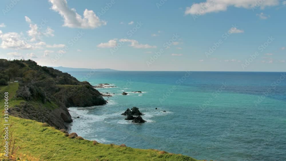 A view of the beautiful Mediterranean Sea from mountain cliffs by yellow wildflowers - wide pan A view of the beautiful Mediterranean Sea from mountain cliffs by yellow wildflowers - wide pan