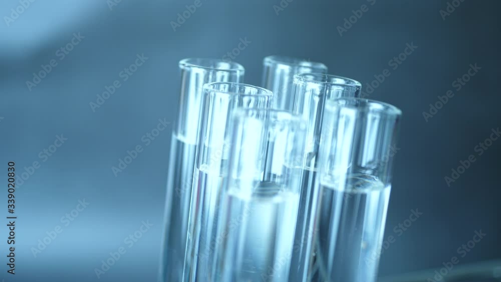 Close up of pipette with liquid inside and water drop in test tubes