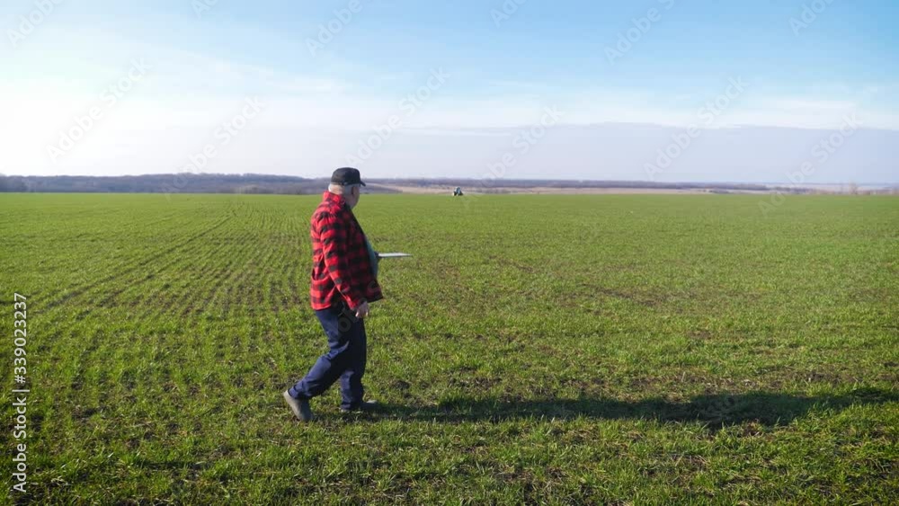 Senior agronomist man looks at a fresh green field after winter. Smart farming, using modern technologies in agriculture. Senior agronomist man looks at a fresh green field after winter. Smart farming, using modern technologies in agriculture.