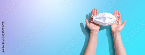 Person holding a white surgical mask overhead view - flat lay photo