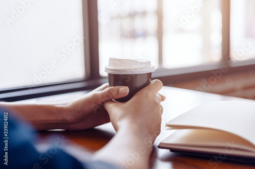 Young girl and hot cup of coffee. Book, pen and tablet on thetable. photo