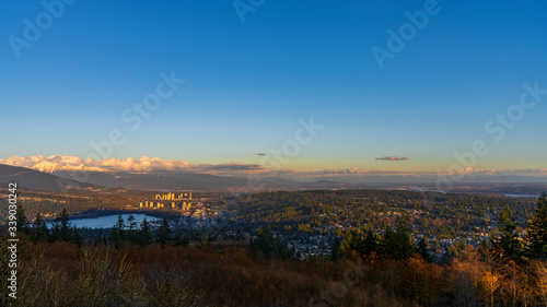 Sunset panorama over valley with sea inlet in foreground and alpine mountain on horizon 