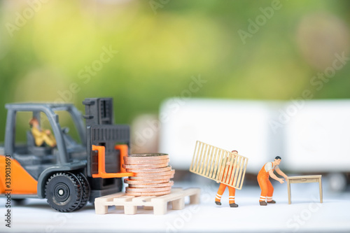 Miniature people: Worker loading box to truck container stack of coin with copy space using as background business shipping, rent container, worldwide transportation logistic concept.