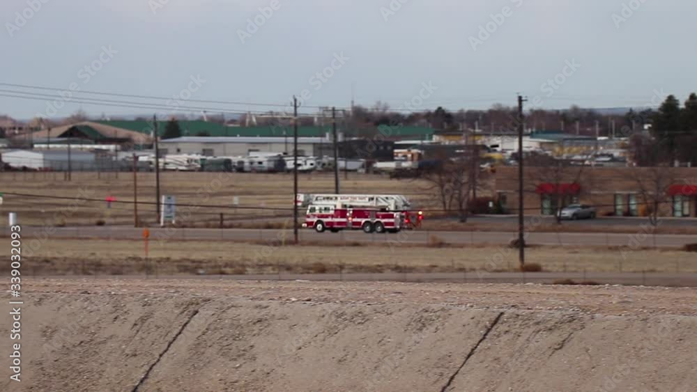 A red firetruck drives quickly down a small highway by the airport in Boise Idaho. A red firetruck drives quickly down a small highway by the airport in Boise Idaho.