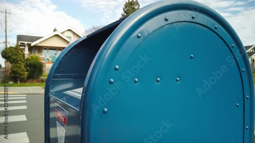 Man sends letter in residential public mailbox on the sidewalk.