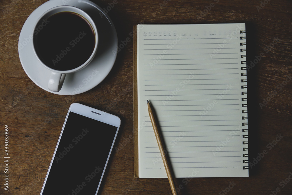 Notebook with coffee and pencil on wood table for writing at home. Work at home concept. Notebook with coffee and pencil on wood table for writing at home. Work at home concept.