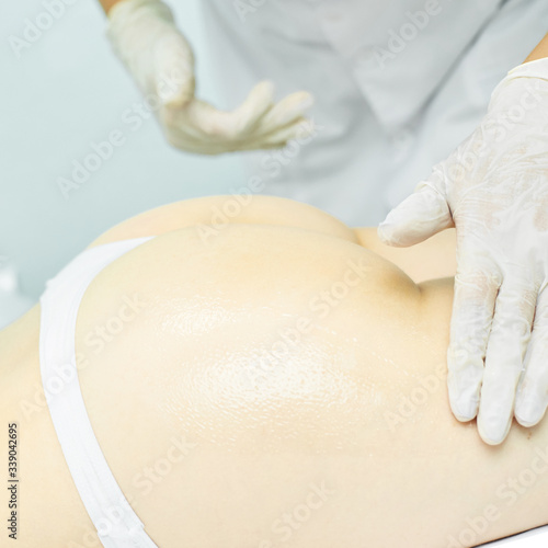 Body massage with oil. Doctor cosmetologist hands. Anti cellulite medical procedure. Legs back treatment. photo