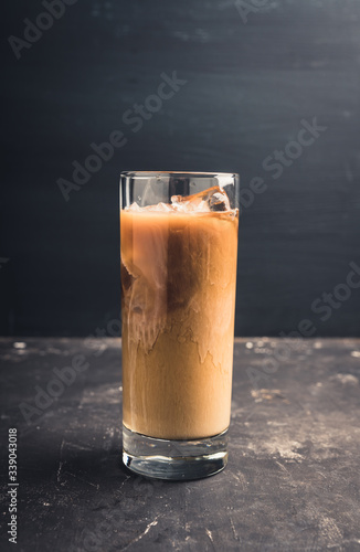 Iced coffee with cream on the rustic background. Selective focus. Shallow depth of field. 