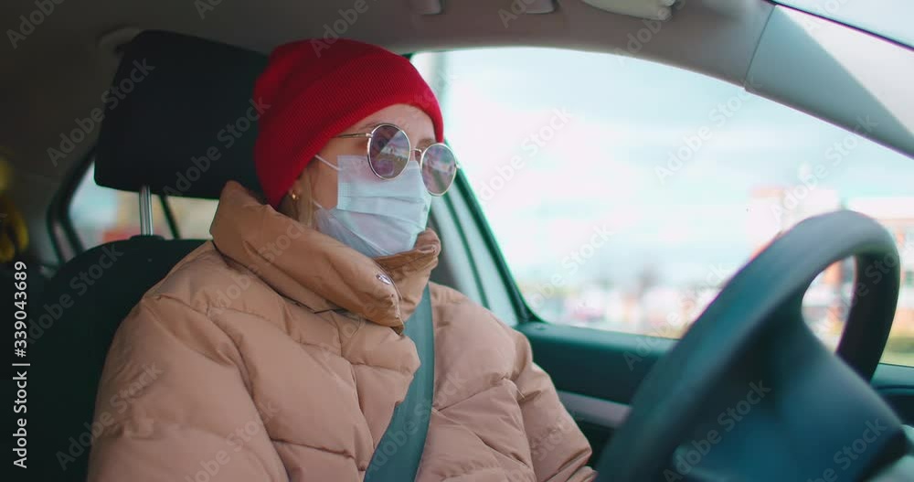 Slow motion: Young woman in protective sterile medical face mask in a car, pandemic coronavirus concept. Slow motion: Young woman in protective sterile medical face mask in a car, pandemic coronavirus concept.