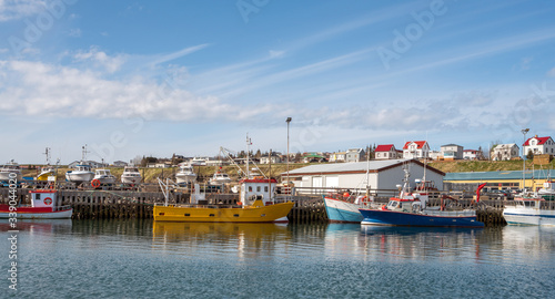 The charming city and the fishing harbour of Husavik in the northern part of Iceland. Photographed from sea during sunny day in spring.