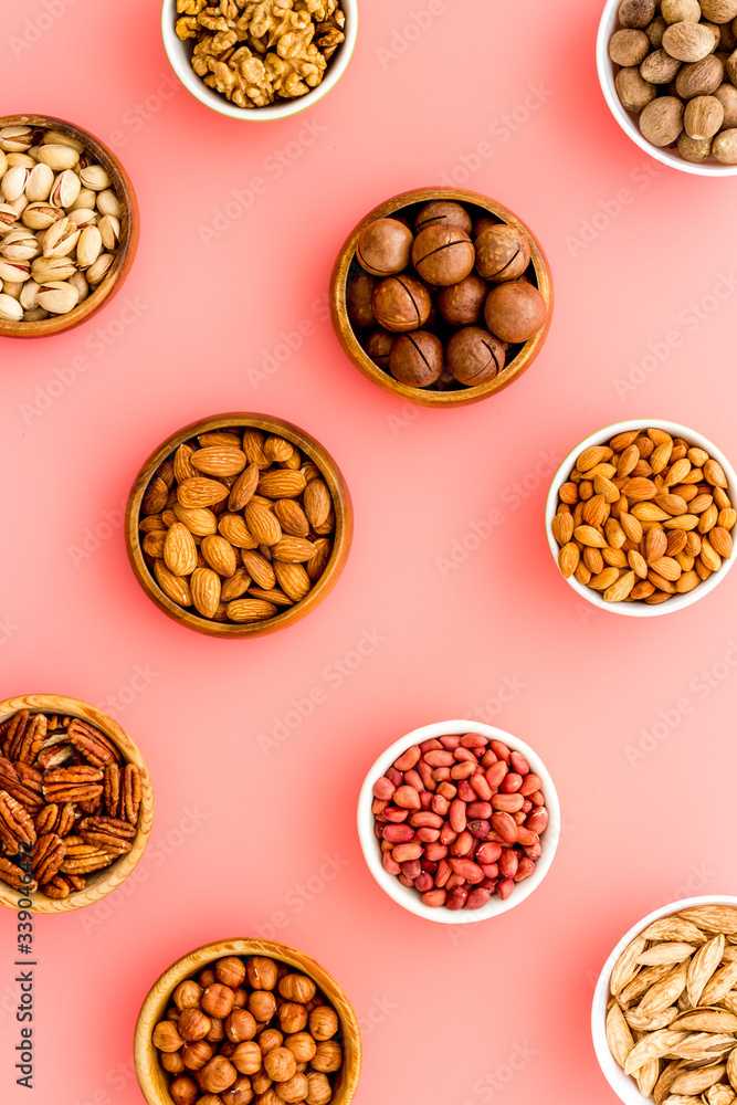 Set of macadamia, hazelnut, walnut, almond, pistachio, pecans nuts on pink background top-down pattern Set of macadamia, hazelnut, walnut, almond, pistachio, pecans nuts on pink background top-down pattern