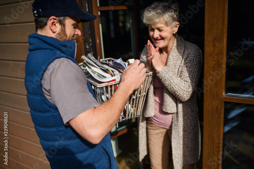 Canvas Print Man courier delivering books and magazines to senior woman.
