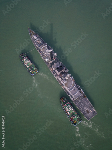 Aerial view of boats towing the larger ships in sea harbor.
