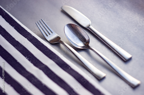 Cutlery on a gray table next to a striped napkin, 
