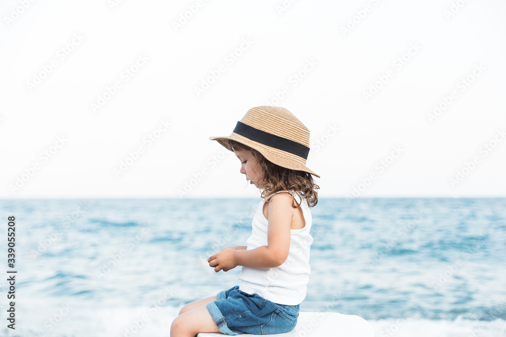 Happy child girl in hat on the beach with sea view.Vacation,summer concept