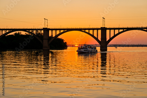 A bridge on a river lit by the sun at sunset. Evening river landscape.