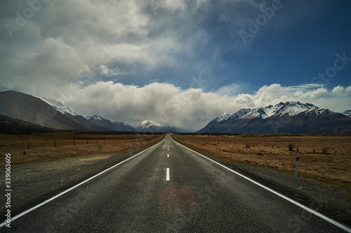 The starlight highway leading off into the distance towards a mountain range with snow covered peaks at Mt Cook in New Zealand