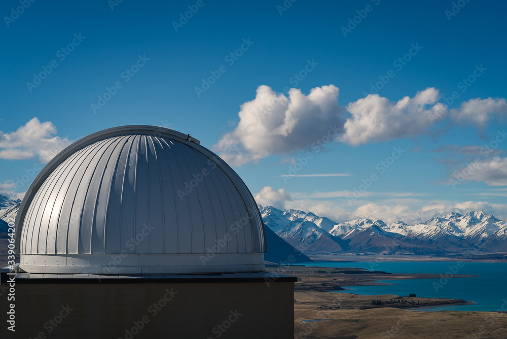 Bird’s eye view from Mt St John Observatory, with a view of the observatory dome, grassy hill overlooking a lake below with snow capped mountains in the background in Tekapo in New Zealand South Islan Bird’s eye view from Mt St John Observatory, with a view of the observatory dome, grassy hill overlooking a lake below with snow capped mountains in the background in Tekapo in New Zealand South Islan