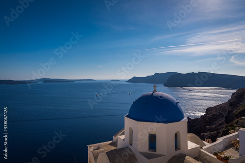 Overlooking the beautiful blue Caldera ocean with the famous blue dome churches of Oia in the foreground in Santorini, Greece. 