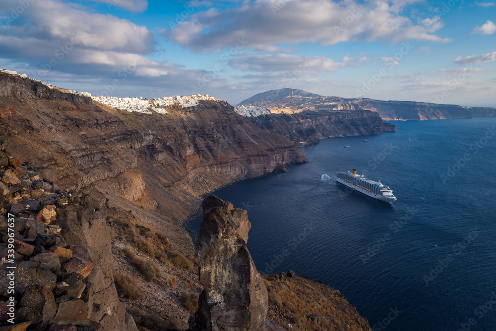Looking over the blue Caldera ocean towards the town and cliffs of Fira on the island of Santorini, Greece