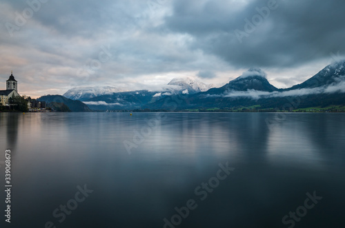 A scenic view of St Wolfgangseelake in Austria with misty mountains in the background