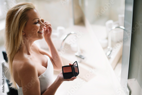 Young woman in the hotel bathroom, refreshing herself and apply makeup 