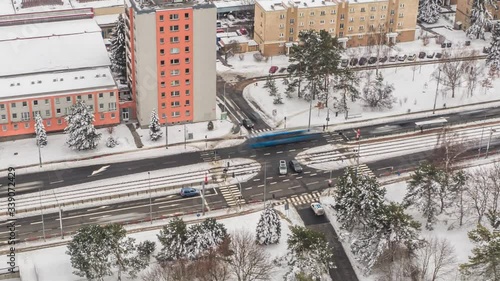 Aerial view of one of the crossroads of the Evropska avenue in Prague. There is busy traffic on the road, cars, trams, and busses rushing by. Streets are covered with fresh snow. photo