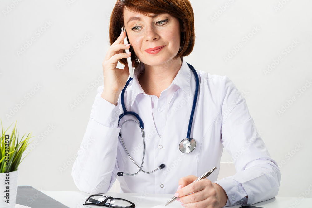 Attractive redhead doctor talking on smartphone Attractive redhead doctor talking on smartphone