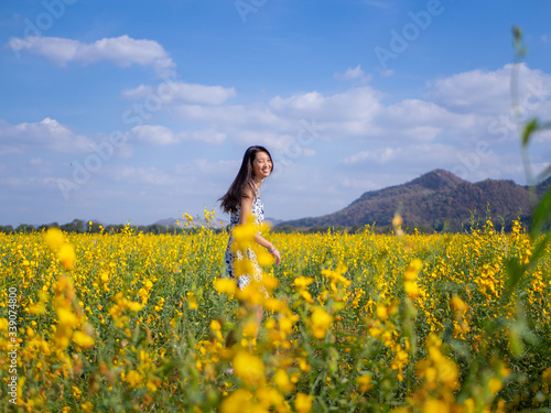 Young happy girl walking on the flower field and enjoying fresh air.