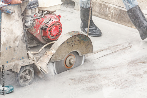 Fotografía Worker using diamond saw blade machine cutting concrete road at construction sit