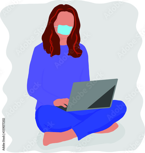 Freelancer girl working on a laptop while sitting on the floor in a medical mask in quarantine
