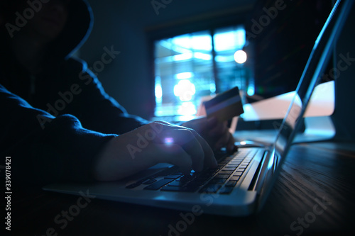 Quadro em tela Hacker with credit card and laptop in dark room. Cyber crime