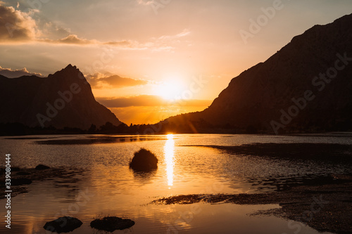 Tajikistan. Fann mountains Summer. Sunset. The orange sun sets among the mountains and lake