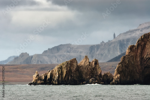 Epic landscape with cliffs and mountains on the sea coast. The majestic nature of the Arctic. Amazing harsh nature of Chukotka. Cape Tkayutun, Bering Sea, Pacific Ocean. Chukotka, Far East of Russia. photo