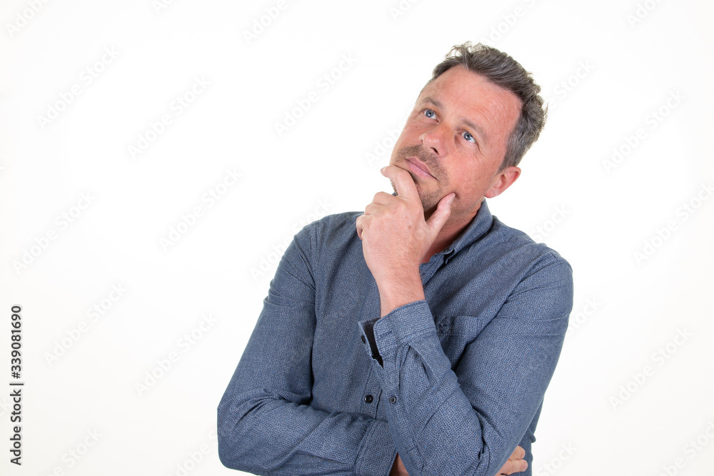 Pensive young bearded man in blue shirt looking up aside copy space posing isolated on white background studio portrait Pensive young bearded man in blue shirt looking up aside copy space posing isolated on white background studio portrait