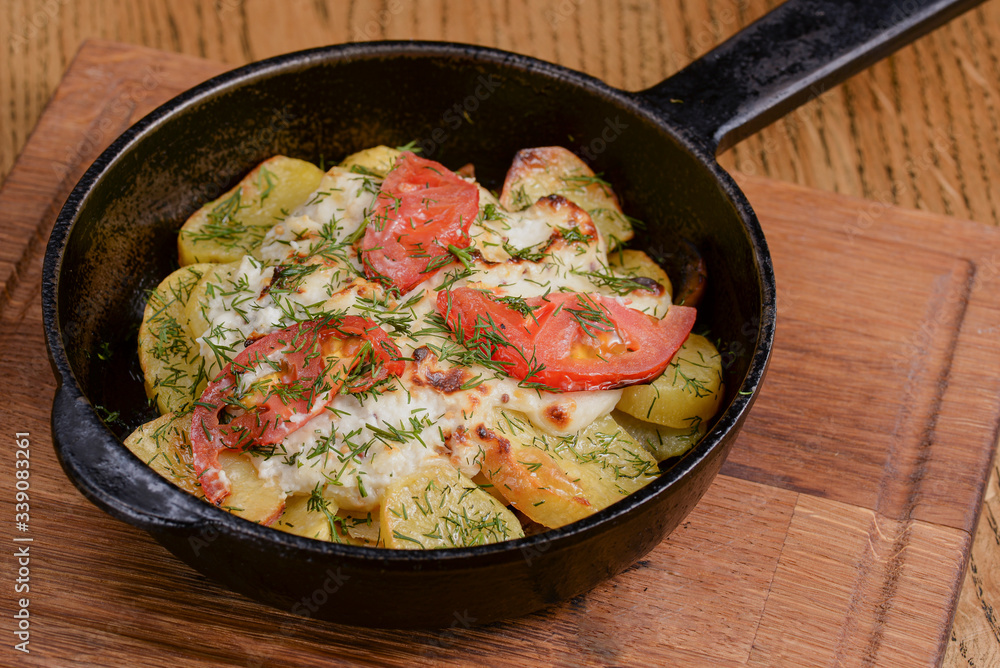 Potato, tomato and onion gratin, with fresh dill served in a pan over rustic wooden background. Potato, tomato and onion gratin, with fresh dill served in a pan over rustic wooden background.